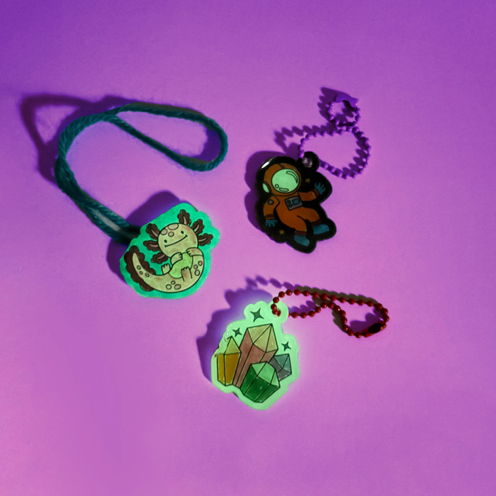 Group of completed and glowing charms from the OOLY Glow Buddies Shrink-Its! DIY Shrink Art Kit